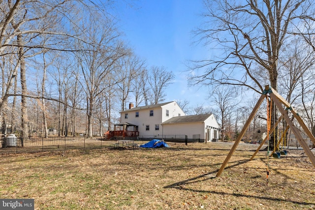 view of yard featuring a deck, a playground, fence, and a garage