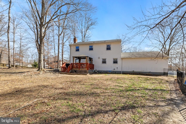 back of house featuring a gazebo, a wooden deck, a chimney, and fence