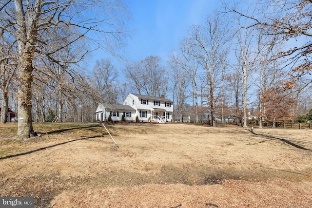 view of front of property featuring a porch, fence, a front yard, and a chimney