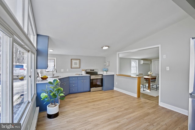 kitchen with light wood-style flooring, appliances with stainless steel finishes, blue cabinets, light countertops, and a sink