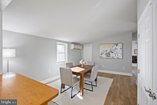 dining room featuring baseboards, vaulted ceiling, wood finished floors, and a wall mounted air conditioner