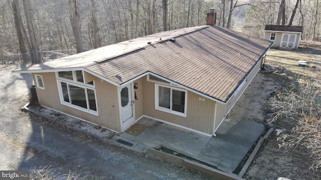 view of front of house with a chimney, a storage unit, and an outbuilding