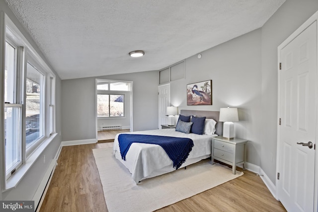 bedroom featuring a textured ceiling, baseboard heating, and wood finished floors