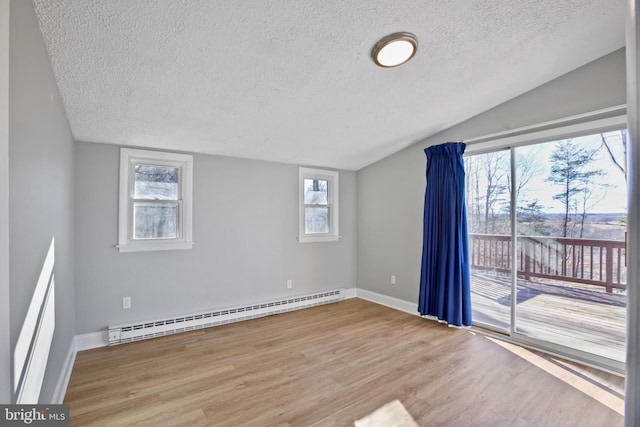 unfurnished room featuring lofted ceiling, a textured ceiling, wood finished floors, baseboards, and baseboard heating