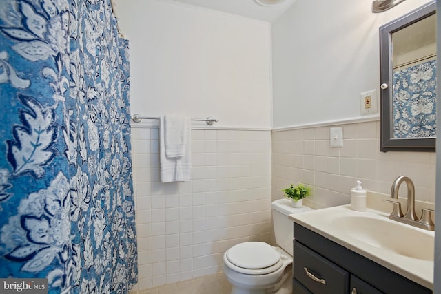 full bathroom with wainscoting, toilet, curtained shower, vanity, and tile walls