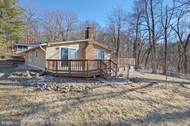 view of front of property featuring a chimney, fence, and a deck