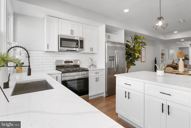 kitchen featuring dark wood-style floors, stainless steel appliances, tasteful backsplash, white cabinets, and a sink