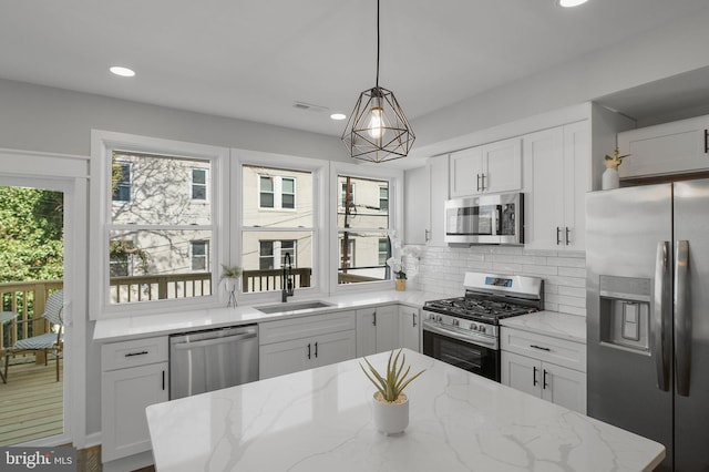 kitchen featuring stainless steel appliances, a sink, visible vents, white cabinets, and backsplash