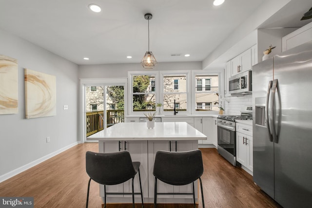 kitchen featuring stainless steel appliances, a center island, dark wood finished floors, and a kitchen bar