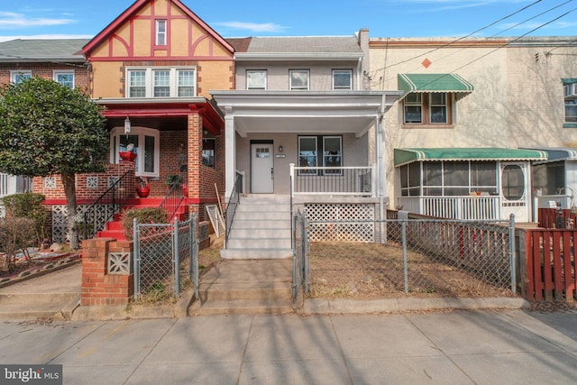 view of front of house with a fenced front yard, a gate, brick siding, and a porch