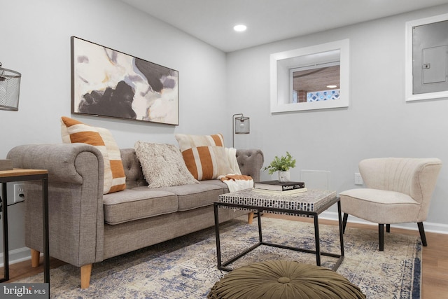 living area featuring recessed lighting, electric panel, baseboards, and wood finished floors