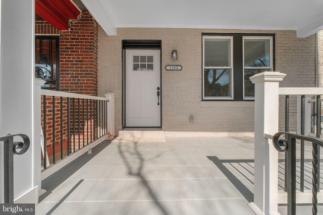 view of exterior entry with covered porch and brick siding