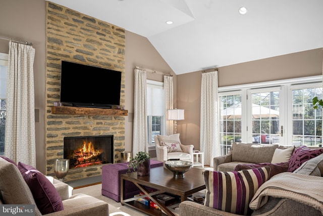 living room featuring a stone fireplace, lofted ceiling, and recessed lighting