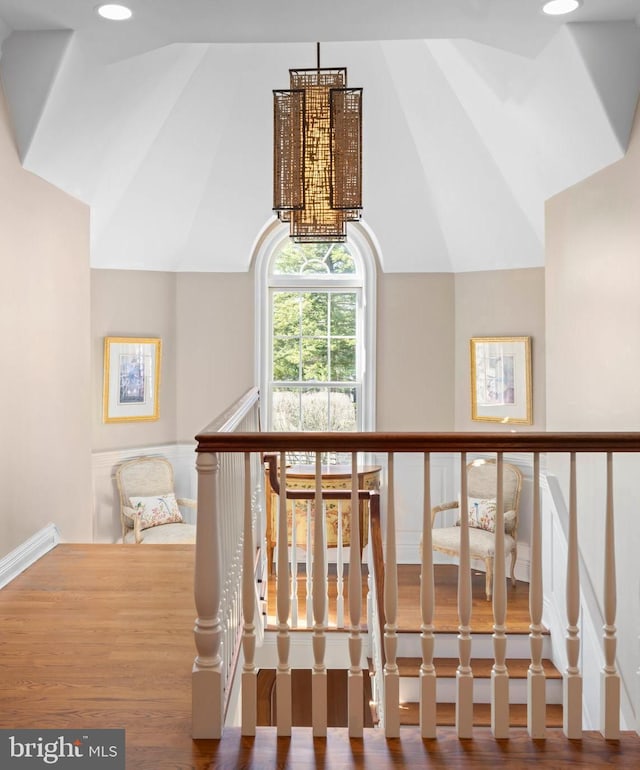 staircase featuring vaulted ceiling, a notable chandelier, and wood finished floors