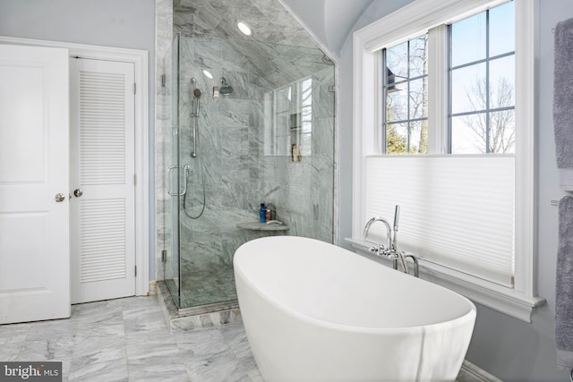 bathroom with a marble finish shower, a freestanding bath, marble finish floor, and vaulted ceiling