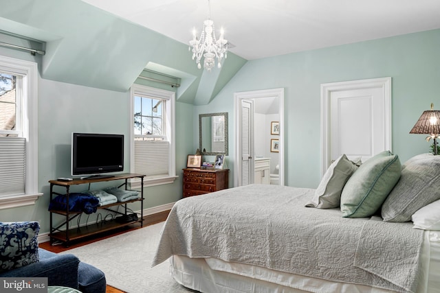 bedroom featuring connected bathroom, wood finished floors, baseboards, vaulted ceiling, and a chandelier