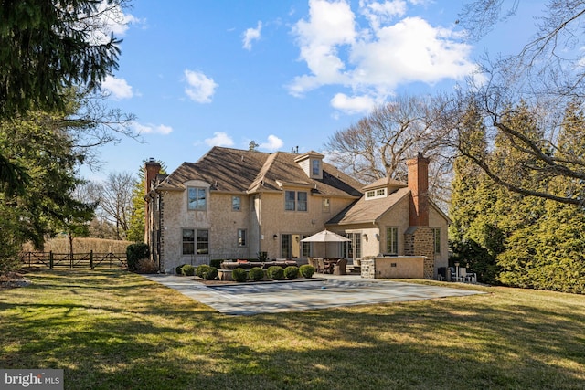 back of property with a lawn, a chimney, a patio, and fence