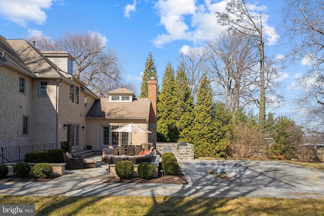 rear view of property featuring stucco siding, a patio, french doors, an outdoor hangout area, and a chimney