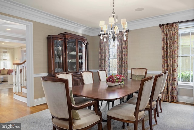 dining area with stairs, a chandelier, light wood-style flooring, and crown molding