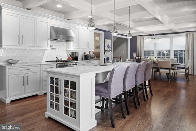 kitchen featuring white cabinetry, wall chimney exhaust hood, dark wood-type flooring, and a sink