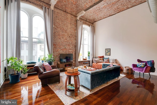 living area featuring brick ceiling, wood finished floors, and a towering ceiling