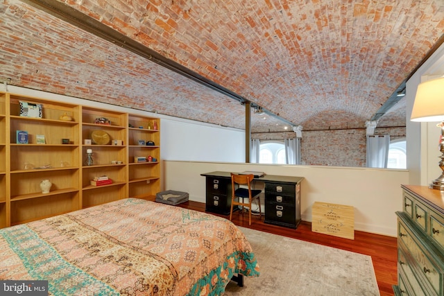 bedroom with brick ceiling, vaulted ceiling, wood finished floors, and baseboards