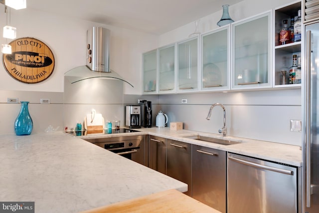 kitchen featuring light stone counters, pendant lighting, glass insert cabinets, appliances with stainless steel finishes, and a sink