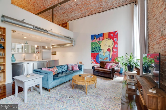 living room featuring brick ceiling, brick wall, a high ceiling, and wood finished floors