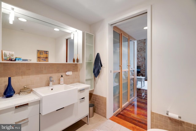 bathroom with recessed lighting, vanity, and tile walls