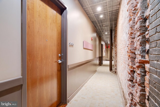 hall with recessed lighting, baseboards, and brick wall