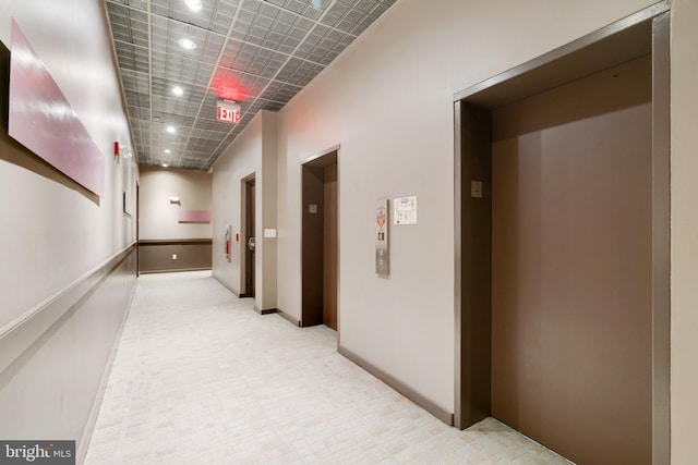 corridor featuring baseboards, recessed lighting, light colored carpet, and elevator