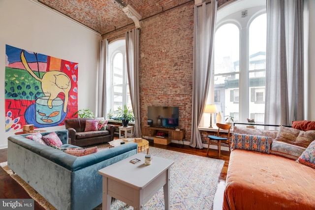 living room with brick ceiling, a high ceiling, and wood finished floors