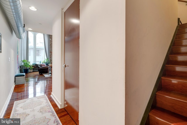 corridor with stairs, baseboards, dark wood finished floors, and recessed lighting