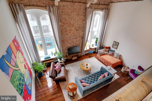 living area featuring brick wall, a fireplace, and dark wood-style flooring