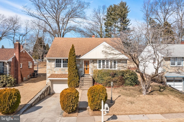 view of front of house with stone siding, roof with shingles, an attached garage, and concrete driveway