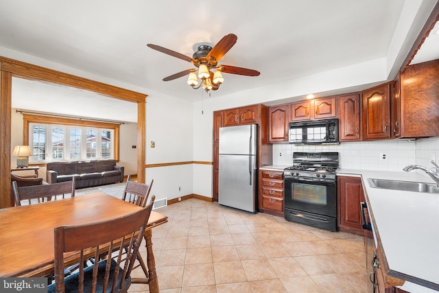 kitchen with light countertops, black appliances, a sink, and decorative backsplash