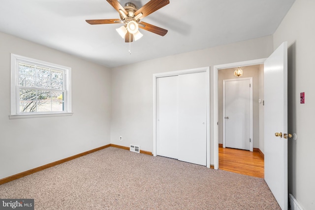 unfurnished bedroom with baseboards, visible vents, light colored carpet, ceiling fan, and a closet