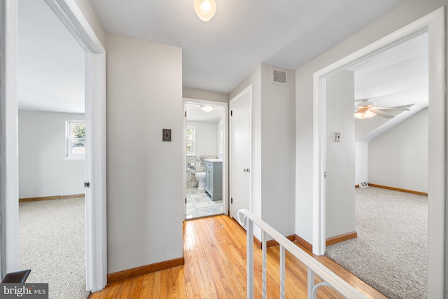 corridor featuring hardwood / wood-style floors, visible vents, and baseboards