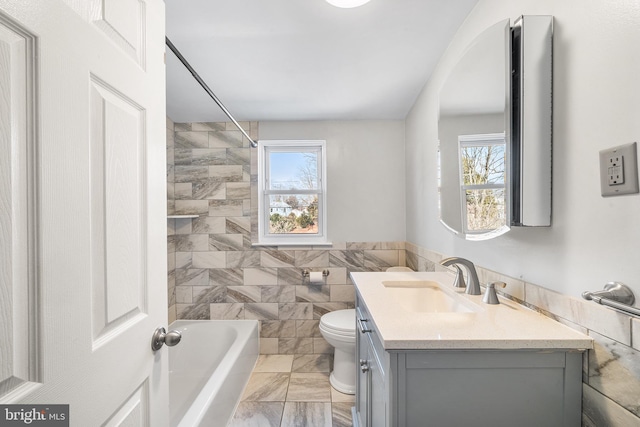 bathroom featuring marble finish floor, tile walls, toilet, washtub / shower combination, and vanity