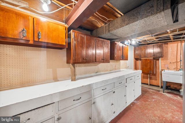 kitchen featuring brown cabinetry, light countertops, and a sink