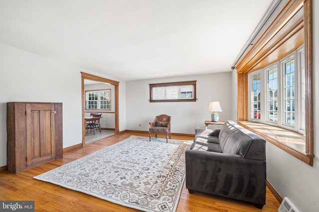 living area with light wood-style flooring, visible vents, and baseboards