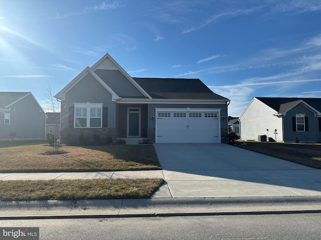 craftsman house featuring concrete driveway, stone siding, a front lawn, and an attached garage