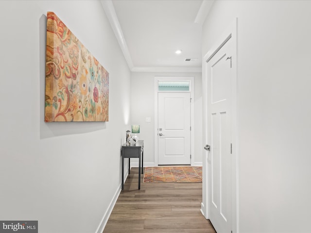 hallway featuring baseboards, visible vents, ornamental molding, wood finished floors, and recessed lighting