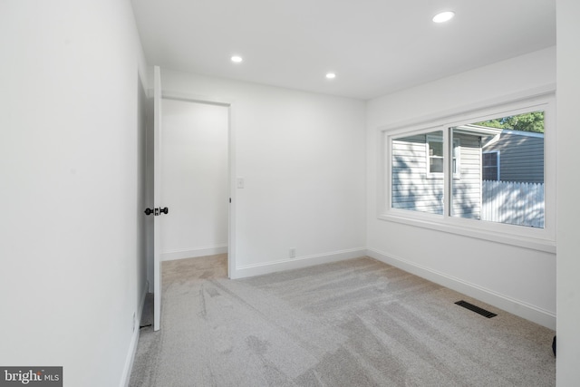 spare room with light colored carpet, visible vents, baseboards, and recessed lighting