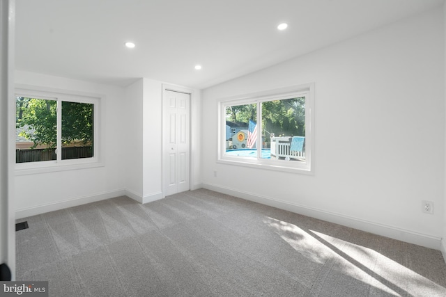 unfurnished bedroom featuring recessed lighting, baseboards, a closet, and light colored carpet