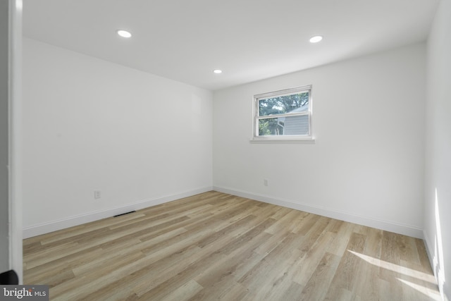 empty room with light wood-style flooring, baseboards, and recessed lighting