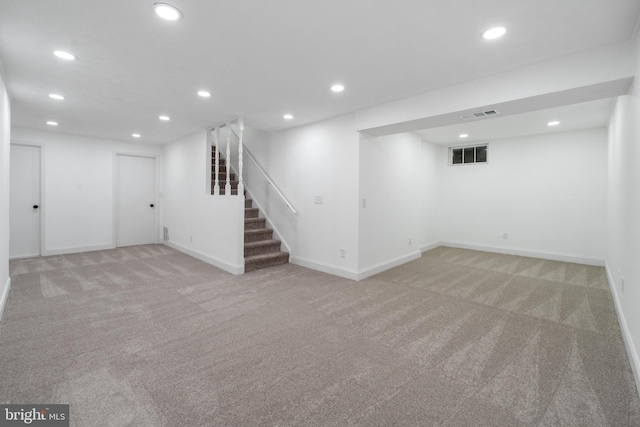 finished basement featuring stairway, recessed lighting, visible vents, and light carpet