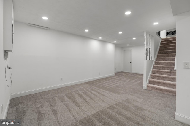 below grade area with recessed lighting, light colored carpet, and stairway