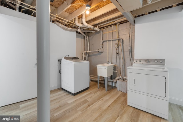 laundry area with laundry area, washing machine and dryer, and light wood-style flooring