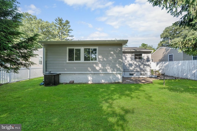 view of side of property with a fenced backyard, a lawn, and central AC